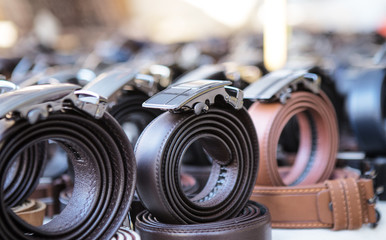 many leather belts on a market stand