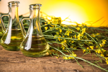 Rapeseed flowers and rapeseed oil in a bottle on the table