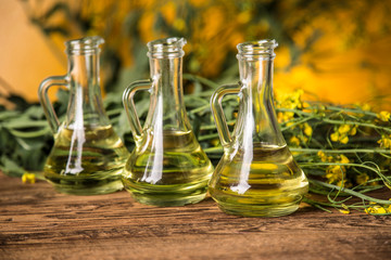 Rapeseed flowers and rapeseed oil in a bottle on the table