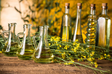 Rapeseed flowers and rapeseed oil in a bottle on the table