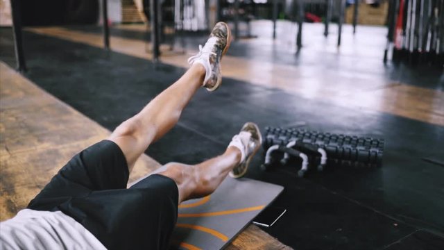 Man in good physical condition does flutter kicks to improve sports training in gym on yoga mat, best exercises for abs and core. Intermediate no equipmetn exersize to endurance. Calisthenics and