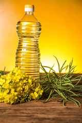 Rapeseed flowers and rapeseed oil in a bottle on the table