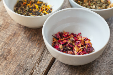 Aromatic dry tea in bowls on wooden background
