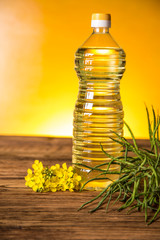 Rapeseed flowers and rapeseed oil in a bottle on the table