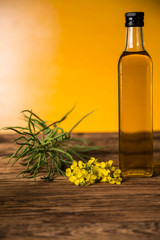 Rapeseed flowers and rapeseed oil in a bottle on the table