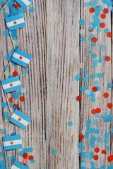 July 9, Independence day of Argentina, the concept of the Day of memory, freedom and patriotism. Mini flags with paper confetti on wooden white background.