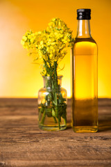 Rapeseed flowers and rapeseed oil in a bottle on the table