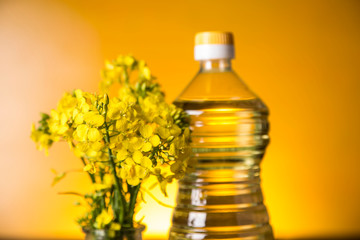 Rapeseed flowers and rapeseed oil in a bottle on the table