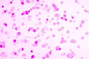 Pink background with many round multicolored confetti.