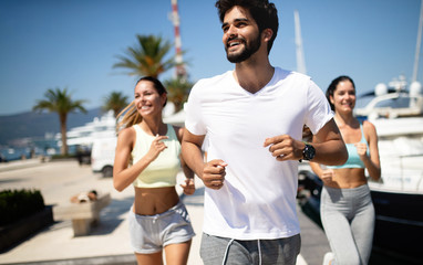 Happy fit people running and jogging together in summer sunny nature