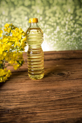 Rapeseed flowers and rapeseed oil in a bottle on the table