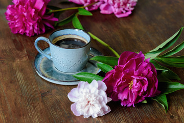 Fototapeta na wymiar A Cup of coffee and peonies on a dark wooden table. Summer morning, romantic mood.