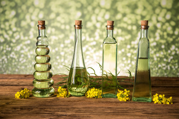 Seeds and rape flowers in bottles and carafes with rapeseed oil