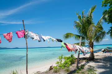 Clothes washed and hanging in tropical sun  and wind to dry. - obrazy, fototapety, plakaty