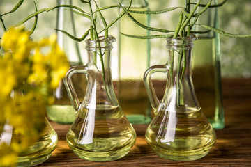 Seeds and rape flowers in bottles and carafes with rapeseed oil