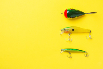 Fishing hooks and baits in a set for catching different fish on a yellow background with copy...