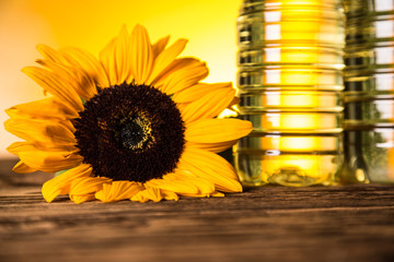 Sunflower oil in a bottle, sunflower flower on a wooden table