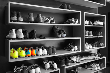 A lot of cleats , soccer boots on shoe rack