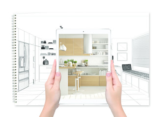 Hands holding tablet showing kitchen, notebook with blueprint sketch in the background, augmented reality concept, application to simulate furniture and interior design products
