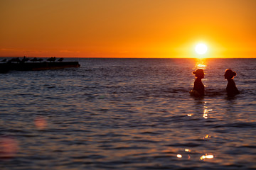 Kąpiące się dziewczyny w morzu o zachodzie słońca