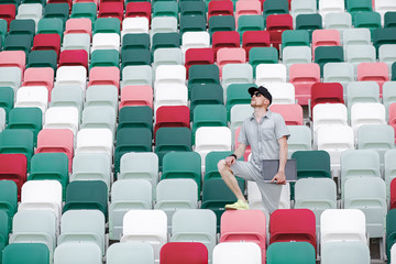 Naklejka premium journalist on an empty sports field with a laptop