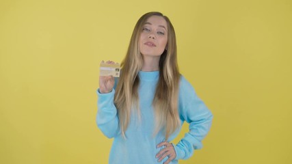 Teen holds shopping bags and a gold credit card. yellow screen. 4 K - Powered by Adobe