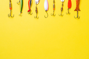 Fishing hooks and baits in a set for catching different fish on a yellow background with copy...