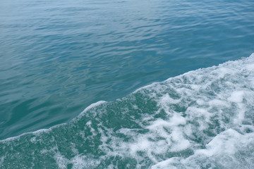 Trail on the water from the boat, sea waves bubble foam from boat. Stock photo image of ocean waves and sea foam caused by the sail of a speed boat, water surface behind of fast moving motor boat