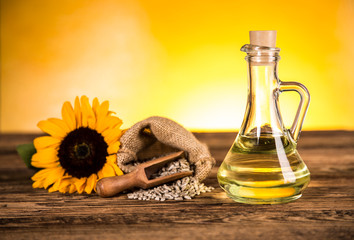 Sunflower oil in a bottle and sunflower flowers and sunflower seeds in a sack - obrazy, fototapety, plakaty