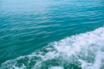 Trail on the water from the boat, sea waves bubble foam from boat. Stock photo image of ocean waves and sea foam caused by the sail of a speed boat, water surface behind of fast moving motor boat