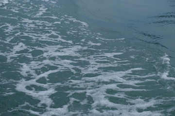 Trail on the water from the boat, sea waves bubble foam from boat. Stock photo image of ocean waves and sea foam caused by the sail of a speed boat, water surface behind of fast moving motor boat
