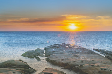 Sun lowers to setting on horizon over water