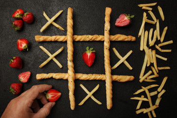 Game of tic tac toe of french fries and strawberry. Choosing healthy vs unhealthy foods. Fit or fat...