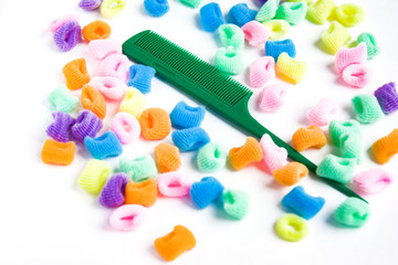 Green plastic comb and bright multi-colored scrunchies on white