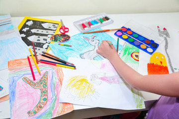 child's hands. Little left-handed child drawing with pencils. Top view, education painting, drawing...