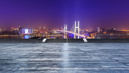 Fototapeta na wymiar Empty wooden board square and bridge buildings at night in Shanghai,China