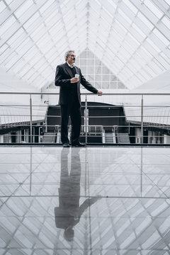 middle-aged business man speaks on a mobile phone. In big business centre. With cup of coffee in hand