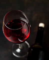 A bottle of wine and a glass of wine on a concrete background.