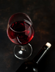 A bottle of wine and a glass of wine on a concrete background.