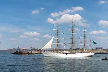 Fototapeta na wymiar Antique tall ship, vessel leaving the harbor of The Hague, Scheveningen under a sunny and blue sky