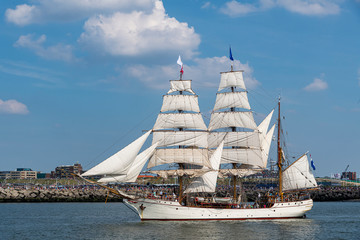 Fototapeta na wymiar Antique tall ship, vessel leaving the harbor of The Hague, Scheveningen under a sunny and blue sky