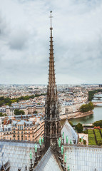 The spire of Notre Dame de Paris, panoramic view of Paris and river Seine from the roof of Notre Dame cathedral, France. Cloudy weather.