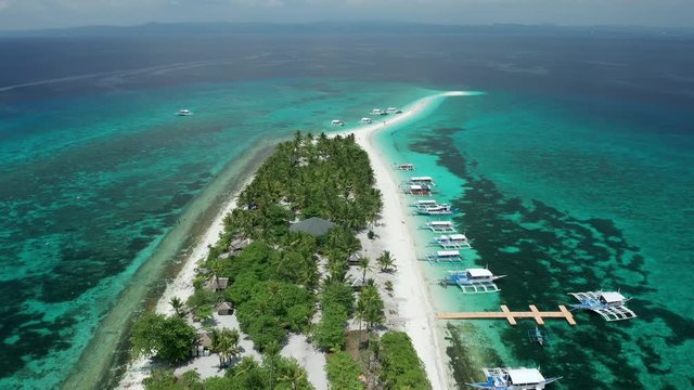 Aerial view of a tiny, green tropical island with a large sandbar surrounded by coral reef (Kalanggaman Island)