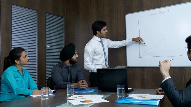 Indian manager presenting his monthly sales report to his senior colleagues - corporate office. Young Indian boss discussing market strategy for a new product launch