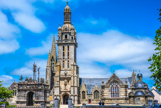 France, Brittany, Pleyben, wayside cross and church of St Germain l'Auxerrois in the parish enclosure