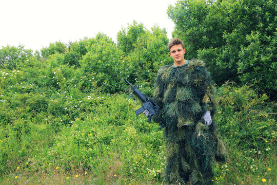 Teenager in ghillie suit with a machine gun