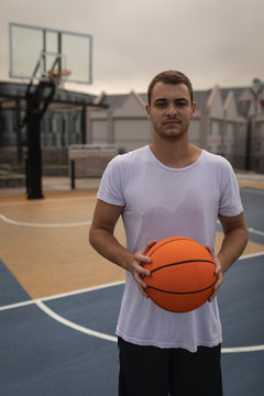 Man holding a basketball standng in playground 