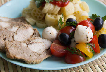 Chicken, horns and salad with tomatoes, mozzarella and olives