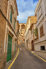 Narrow street with typical houses in historic Arta town on a sunny day, Majorca island, Spain