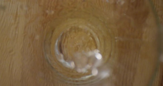 Closeup shoot of water being poured in the glass standing on the table